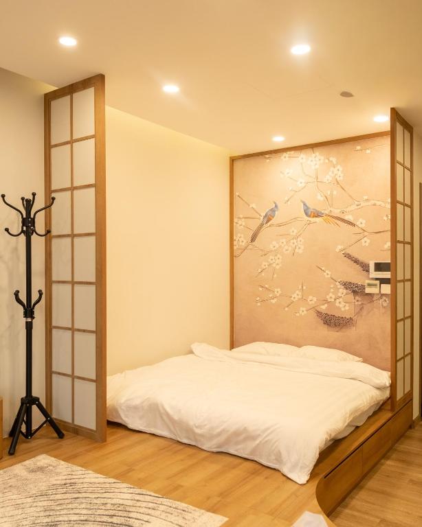 a bedroom with a bed with a painting on the wall at Sakura Room Ở Space Ecopark in Kim Quan