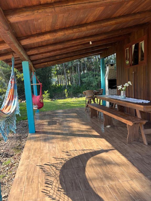 Un porche de madera con una mesa de picnic y una hamaca. en Pousada dos Sonhos - Timbé do Sul, en Timbe do Sul