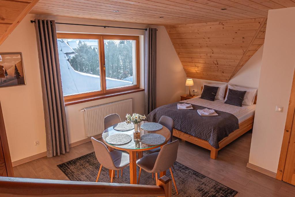 een slaapkamer met een bed, een tafel en een raam bij Osada Witów - apartament „Siwa Kopa” in Witów