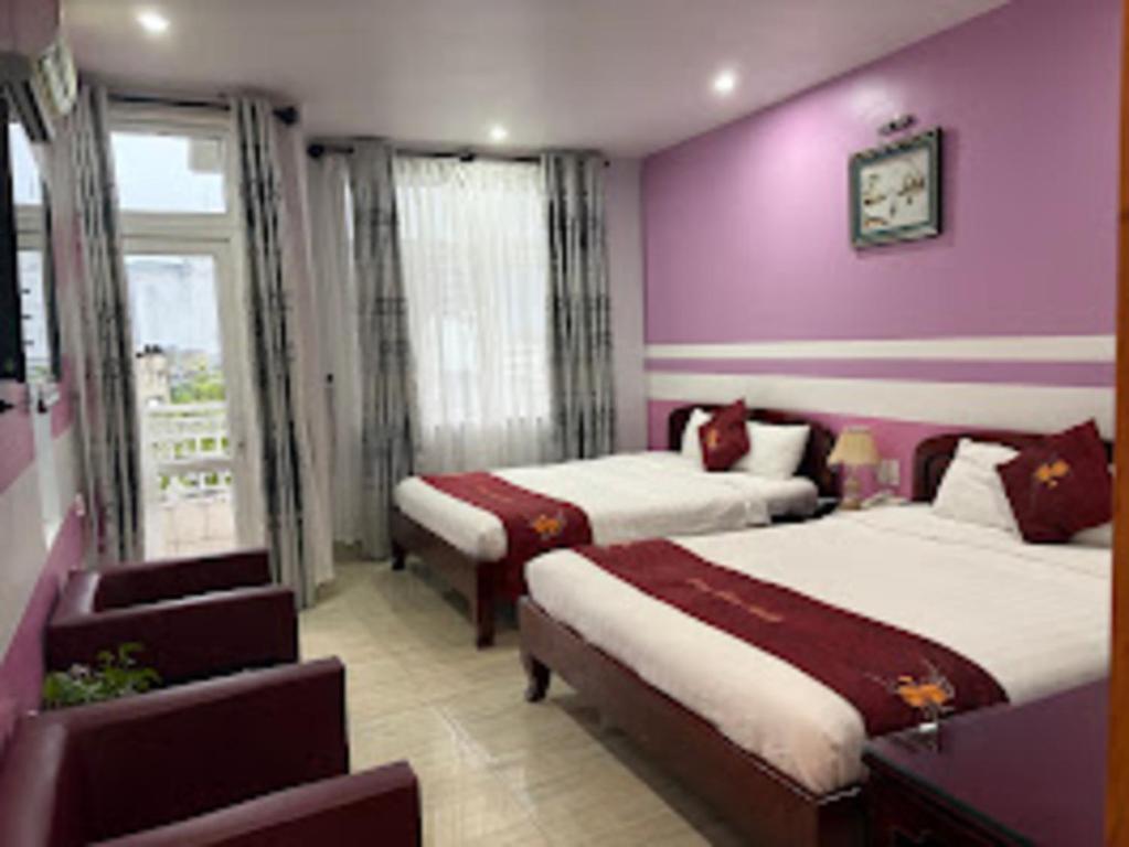 a bedroom with two beds and a purple wall at rubyhotel in Hue