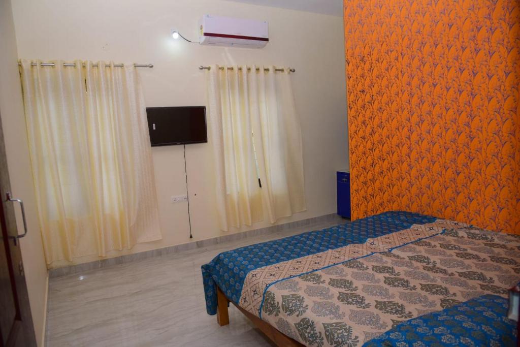 Un dormitorio con una cama con una pared naranja. en AB Island Homestay, en Munroe Island
