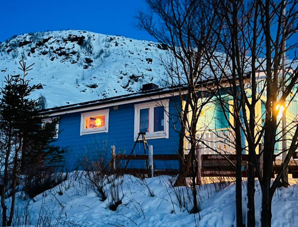 a blue house in the snow with a snow covered mountain at Seiland BlueDream HolidayHome in Skakkebakken