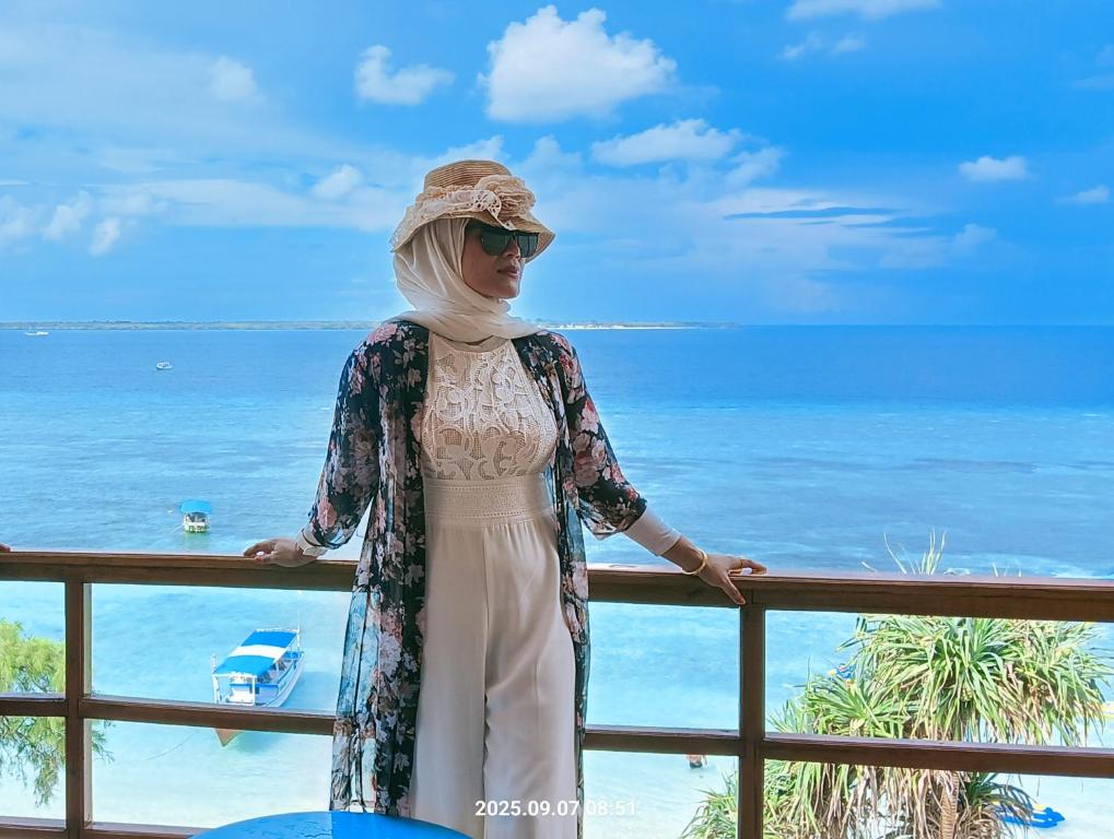 a woman standing on a balcony overlooking the ocean at Casablanca Bira Resort in Tabutule