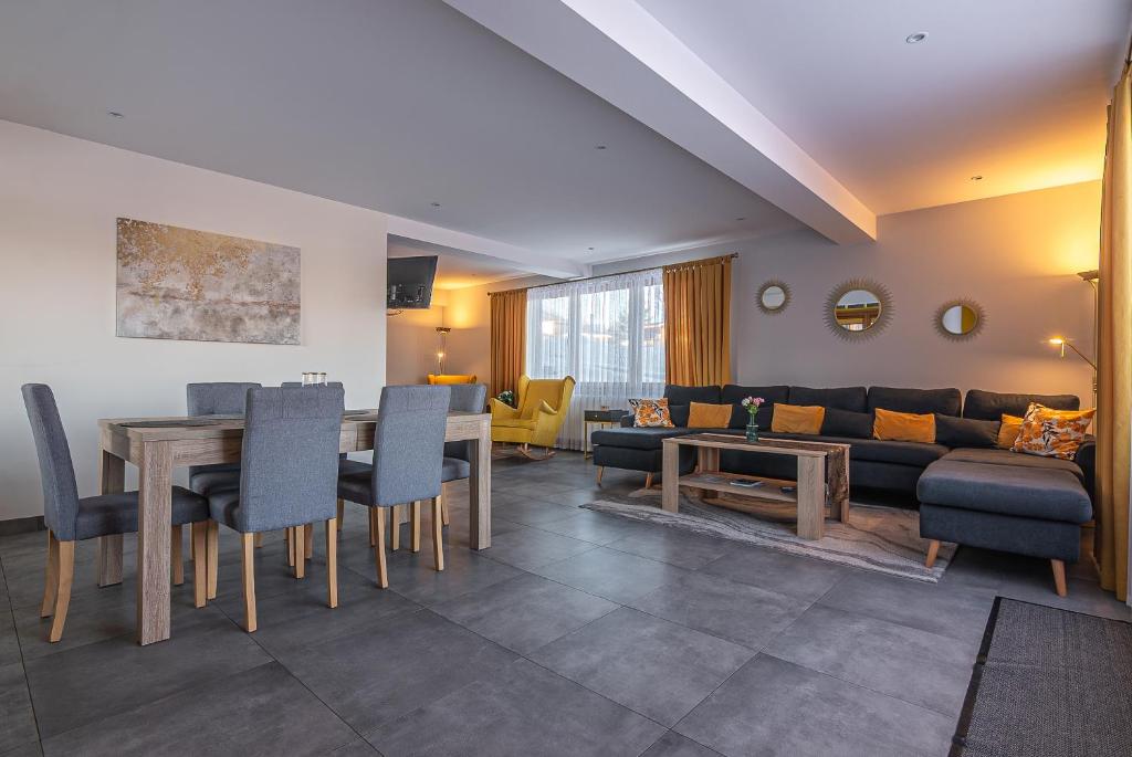 een woonkamer met een bank, een tafel en stoelen bij Osada Witów - Dolina Złota in Witów