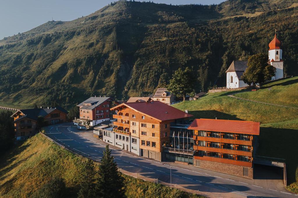 a town on a hill with a church and a mountain at Boutique Hotel die Mittagspitze Superior in Damuls