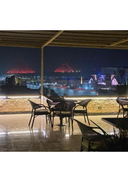 una mesa y sillas con vistas a la ciudad por la noche en Noya Pyramids view hotel, en El Cairo