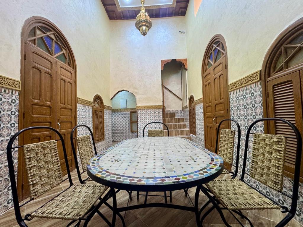 a table and chairs in a room with wooden doors at Riad al anwar in Rabat
