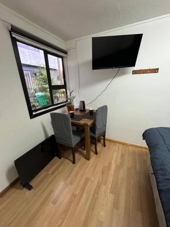a room with a table and a tv on the wall at Habitación independiente con baño privado in Cochrane