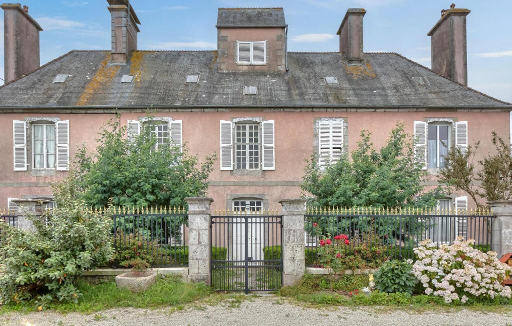 an old pink house with a black fence at Gite Gouville Sur Mer in Gouville-sur-Mer