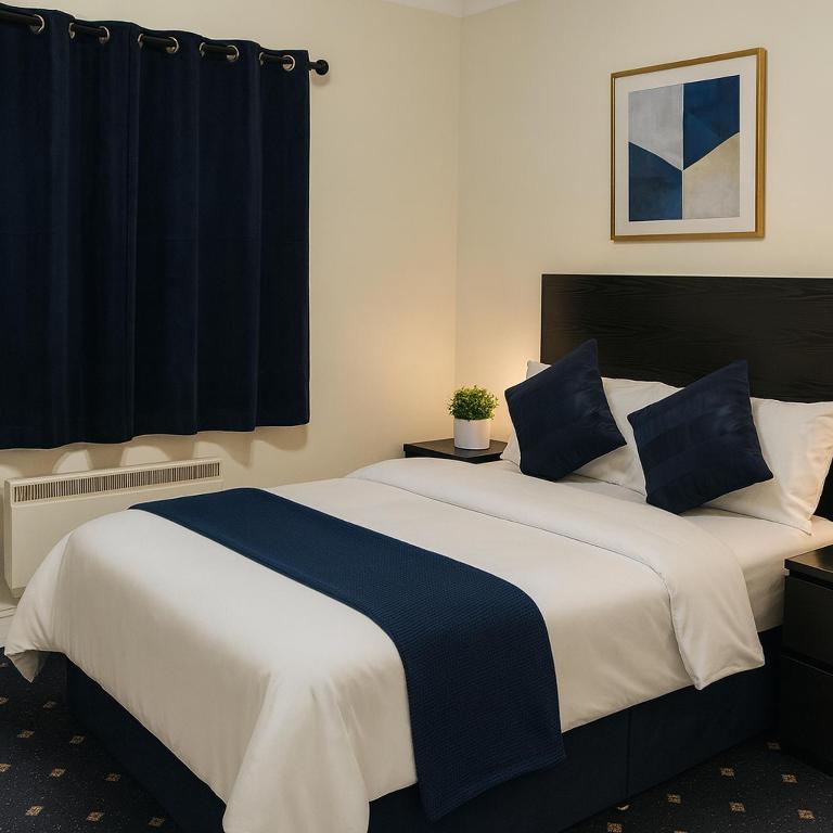 a bedroom with a large bed with blue and white sheets at shabi inn in Ilford