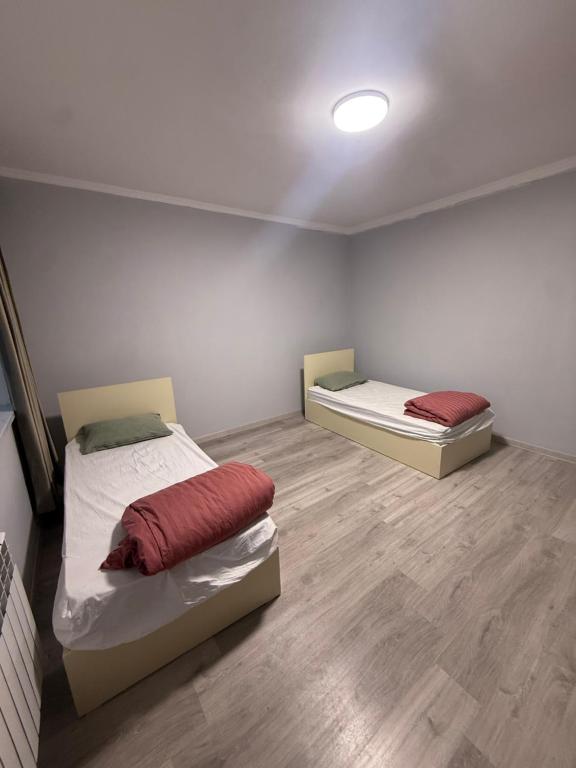 twee bedden in een kamer met houten vloeren bij Rova Home & Hostel in Baku