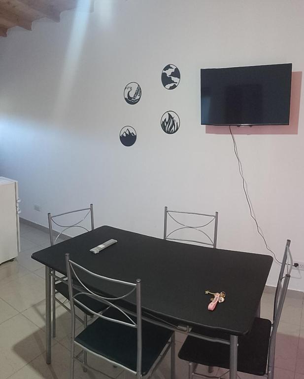 a black table with chairs and a tv on a wall at Sal y Arena in Colonia Chapadmalal