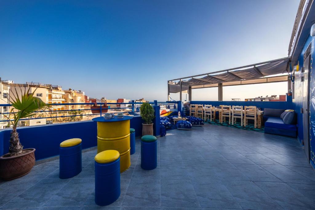 een balkon met blauwe en gele krukken op een dak bij Nomazigh Surf House in Tamraght Ouzdar