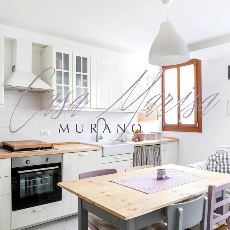 a kitchen with white cabinets and a wooden table at Casa Marisa - facing campo in Murano - Venezia in Murano