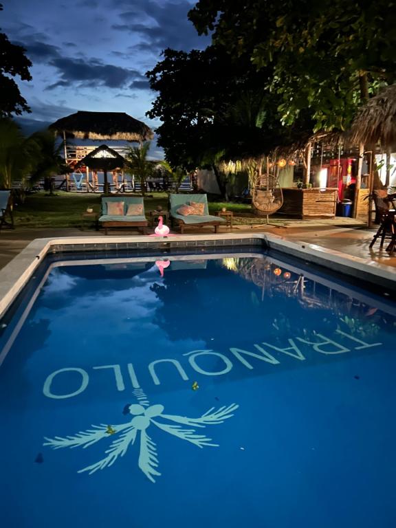 a blue swimming pool with a sign that reads chinawind at Hotel Tranquilo in Las Peñitas
