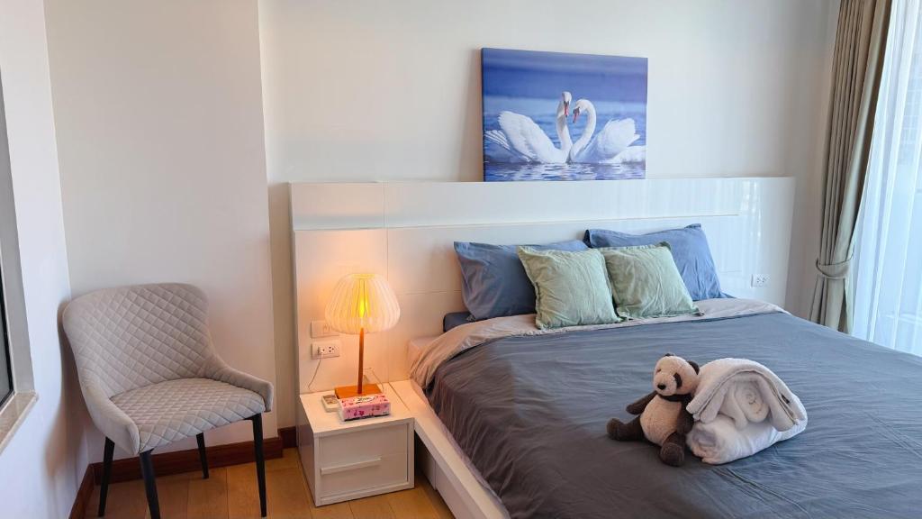 a teddy bear laying on a bed in a bedroom at Astra condo清迈市中心古城高端温馨公寓两卫浴wifi泳池健身房山景城景房 in Chiang Mai