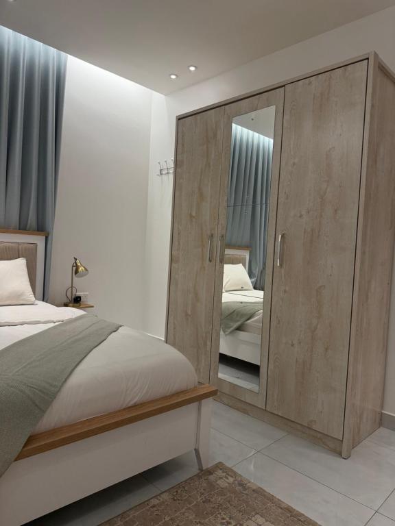 a bedroom with a large wooden cabinet with a mirror at Abu Rakan Apartment in Muscat