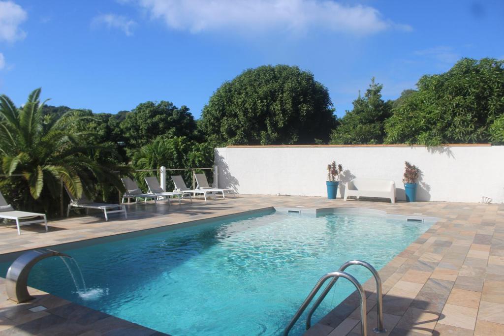 een zwembad met stoelen en een witte muur bij Villa Caryota, Le Marin in Le Marin