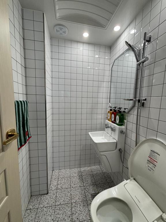 een wit betegelde badkamer met een toilet en een wastafel bij full house in Seoul