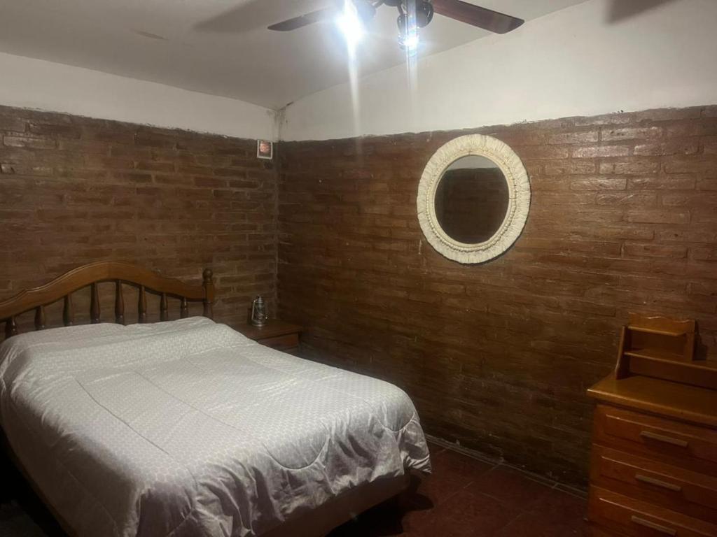 a bedroom with a bed and a mirror on a brick wall at Departamentos Merceditas in San Rafael