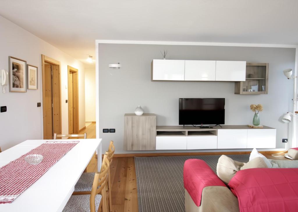 a living room with a red couch and a table at CASA BEBA - Cavalese Olimpiadi 2026 Dolomiti Affitti in Cavalese