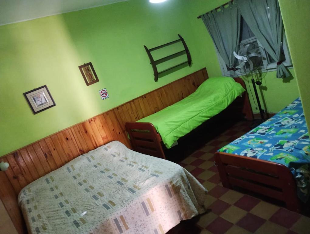 two beds in a room with green walls at Depto San Clemente del tuyu centro in San Clemente del Tuyú