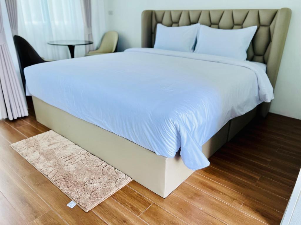 a bedroom with a large bed with white sheets and a rug at Sarona House 4 in Ban Thalat Choeng Thale