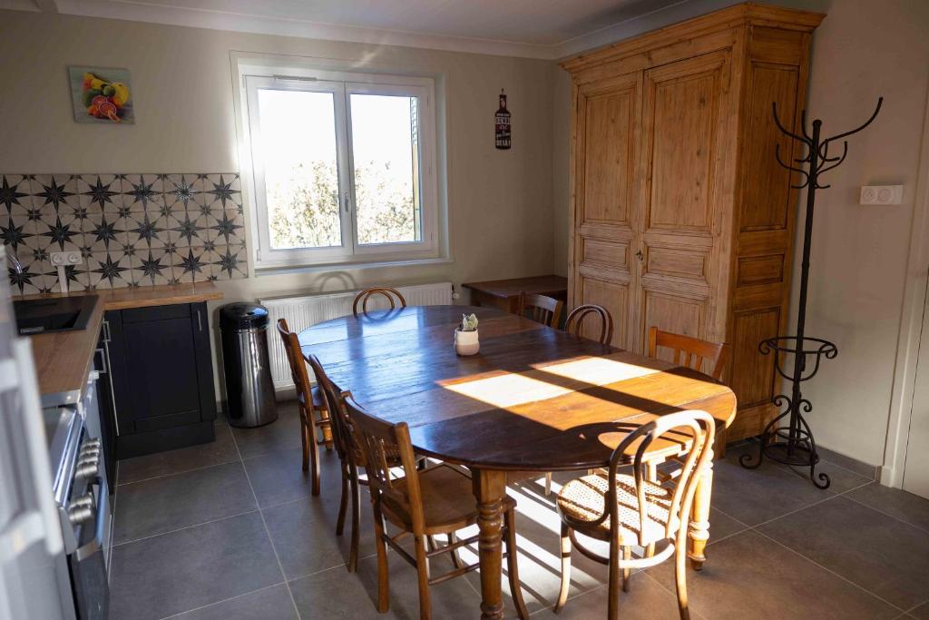 cocina con mesa de madera, sillas y ventana en Les Chambres de MARIE, en Villié-Morgon