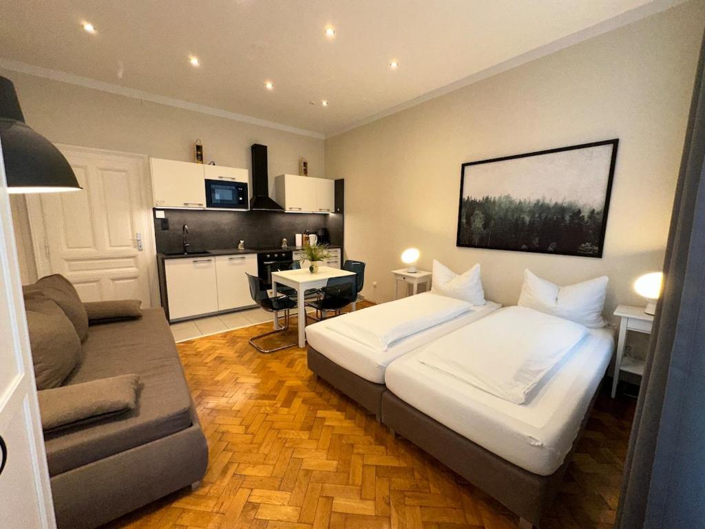a bedroom with a bed and a couch and a kitchen at Wien West Home in Vienna