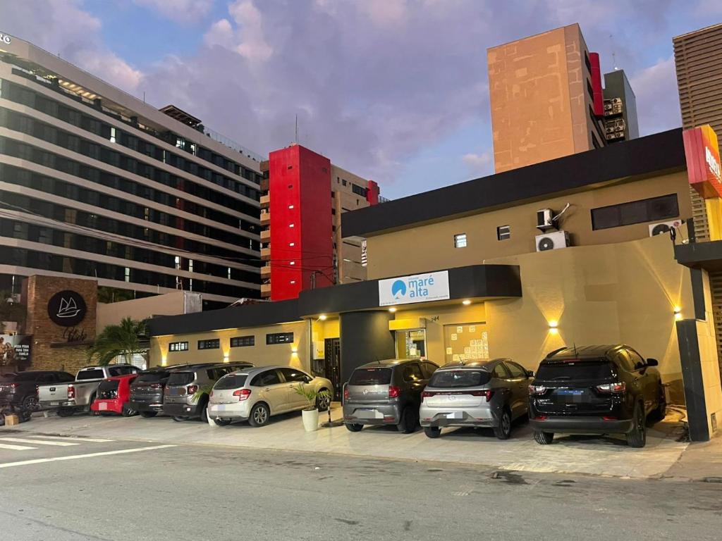 a parking lot with cars parked in front of a building at Pousada Maré Alta Pajuçara in Maceió