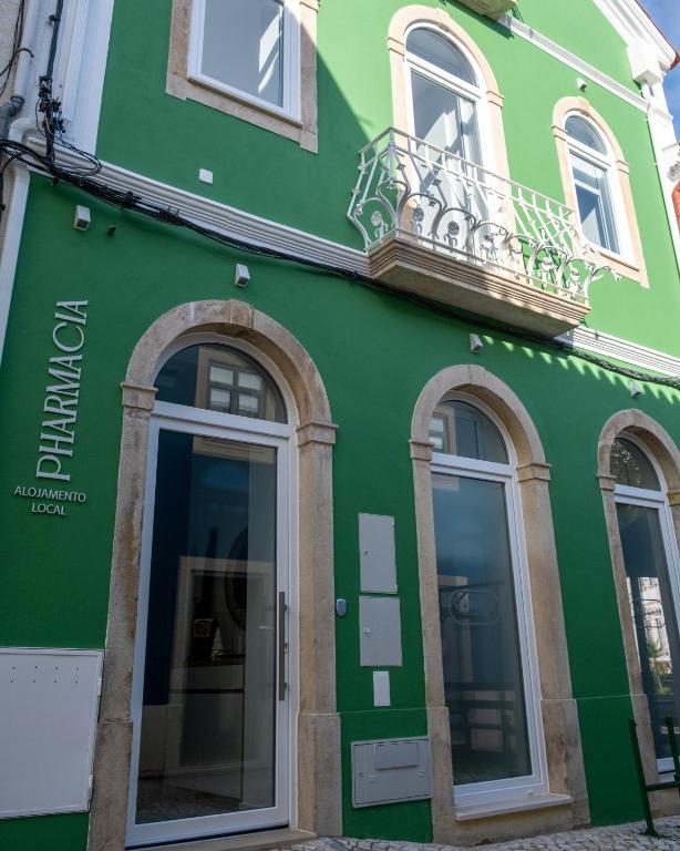 a green building with windows and a balcony at Pharmácia- Alojamento local in Miranda do Corvo
