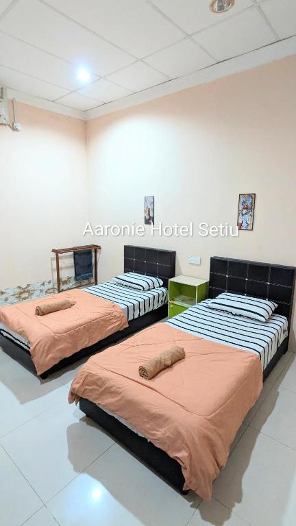 three beds are lined up in a room at Aaronie Hotel Setiu in Kampong Burok