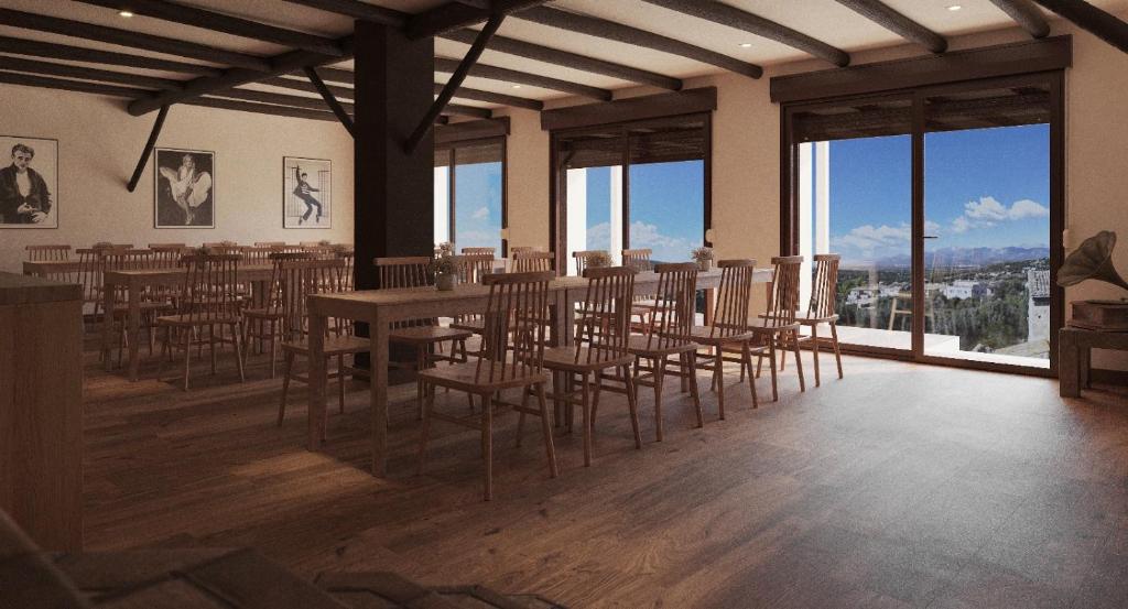 Un comedor con mesa y sillas y ventanas. en My Rooms Hostel Las Salas by My Rooms Hotels - Albergue, en Las Salas