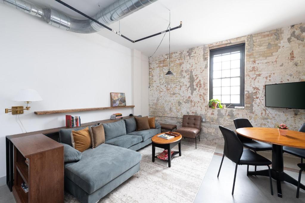 Brewery District 2-Story 2BR Apt Near Fiserv with Rooftop, Gym, and Parking في ميلووكي: غرفة معيشة مع أريكة وطاولة