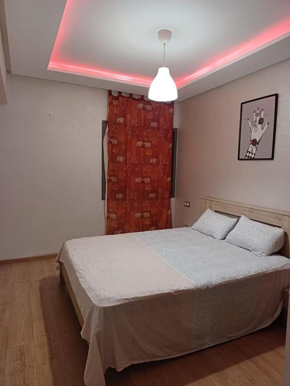 a bedroom with a bed with a pink light at Apartment kamal park E21 in Mohammedia
