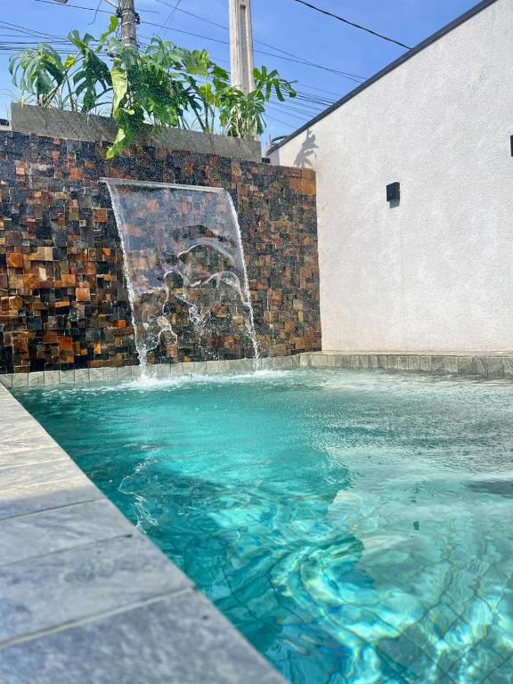 a swimming pool with a water fountain at Casa Malu in Bertioga