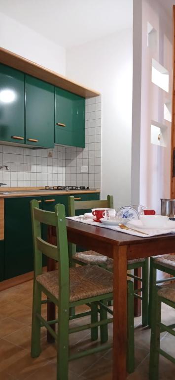 uma cozinha com uma mesa de madeira e armários verdes em Blu Mare em Punta Marina