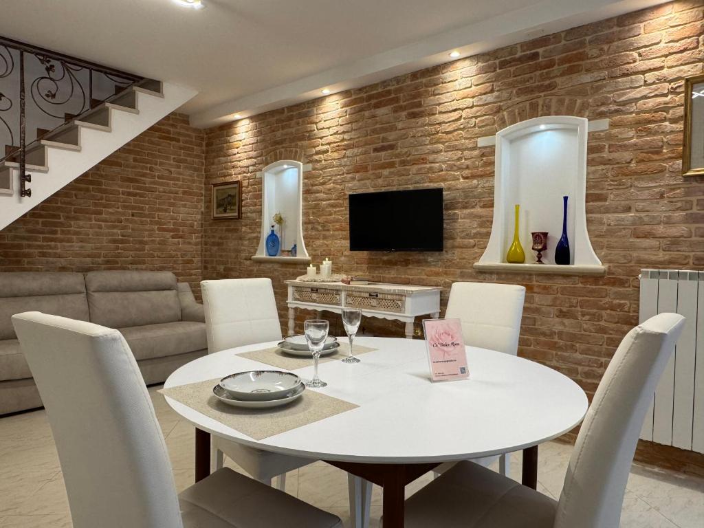 a dining room with a white table and chairs at Ca' Dolce Rosa in Burano