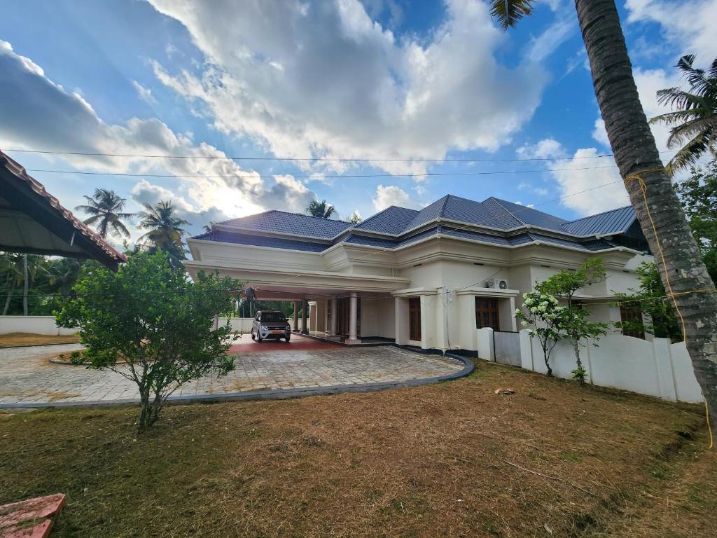 een groot wit huis met een blauw dak bij Abida Mansion 4BHK Near MCP Convention Centre IJK in Irinjālakuda