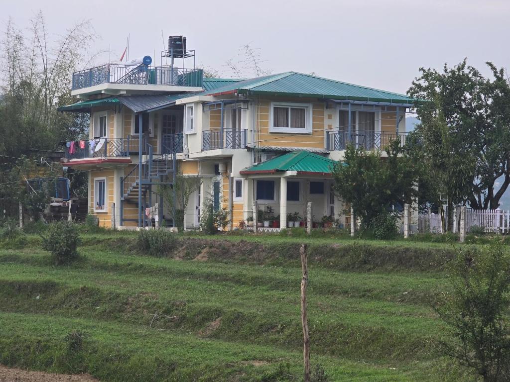 a yellow house with a green roof on a hill at Tapas in Champawat
