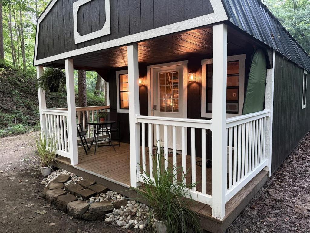 ein kleines Haus mit einer Veranda und einer Terrasse in der Unterkunft Creekwood Cottage in Peru