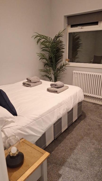 a white bed with two towels on top of it at Victorian Suites - Spacious 2 Bed Apartment in Southport
