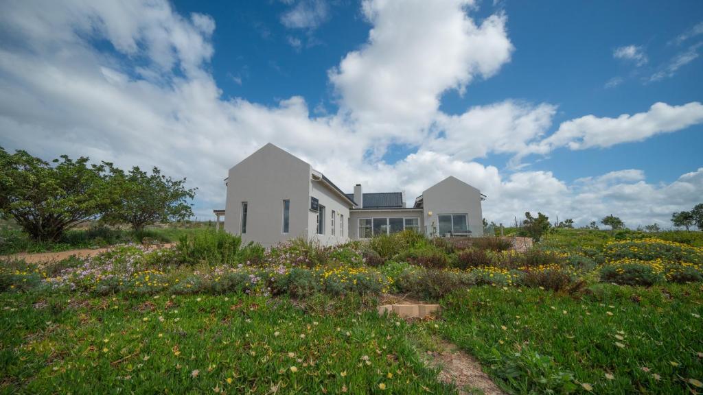 een wit huis met een bloemenveld bij Swallows Rest - Benguela Cove in Hermanus