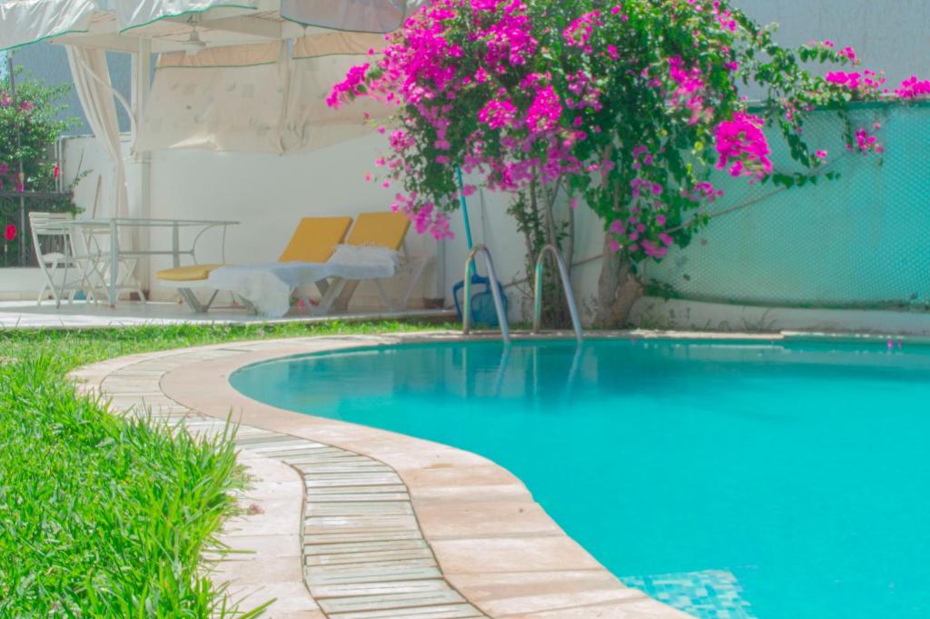 a swimming pool with pink flowers next to a building at Villa avec piscine privée in Potinville