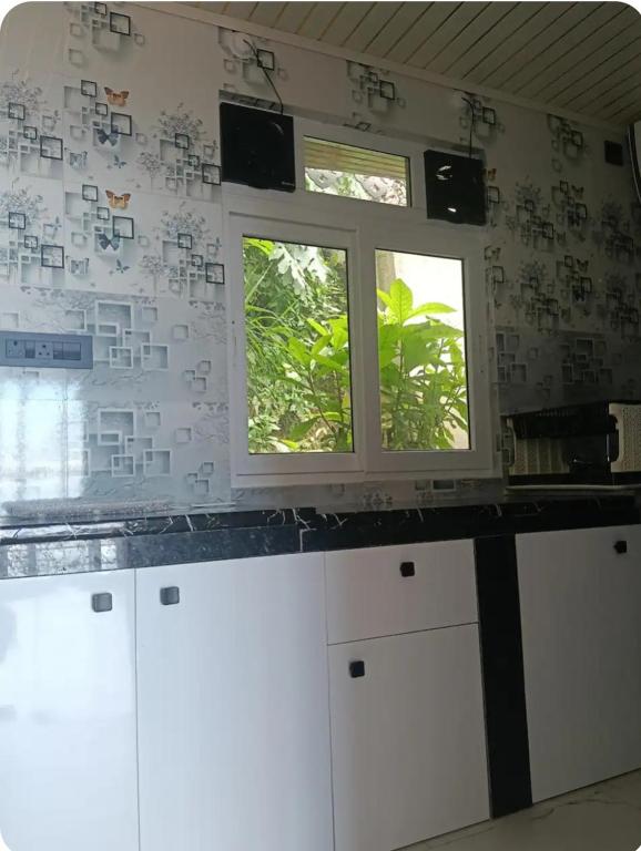 a kitchen with white cabinets and two windows at Wind chimes villa in Karsiyang