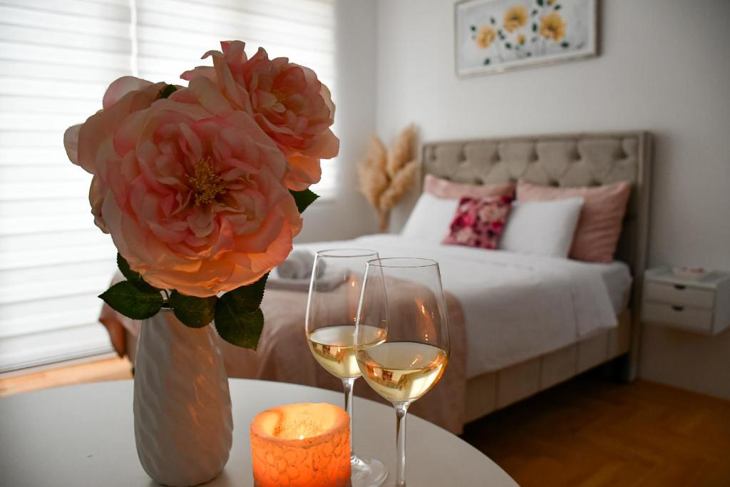 a table with two glasses of wine and a vase with a flower at Apartman Boem Pale in Pale
