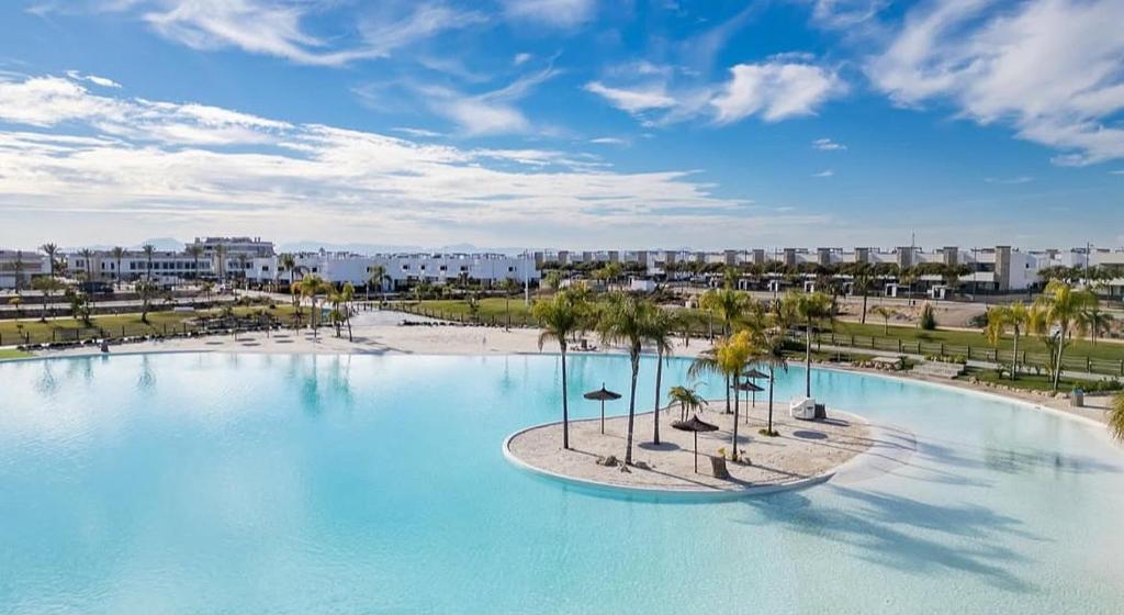 a large swimming pool with palm trees and buildings at Santa Rosalìa - Casa Elsalie in Torre-Pacheco