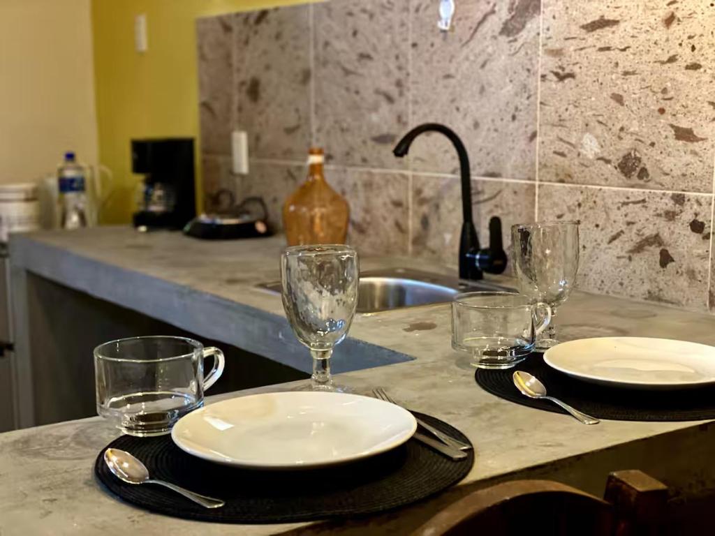 een aanrecht met glazen en borden en een wastafel bij 1-Bed Loft in Oaxaca - Steps from Downtown in Oaxaca City