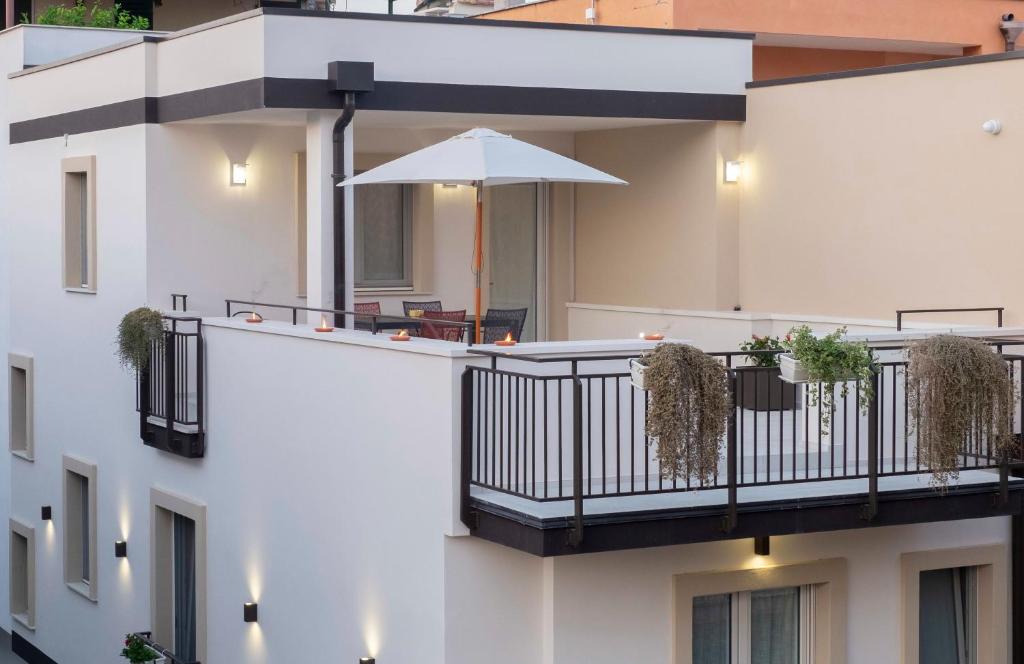 a white building with a balcony with an umbrella at Dimora Fortunato in Bernalda