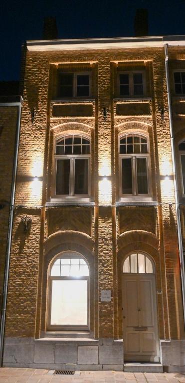 a brick building with three windows and a door at Maison Rose in Ypres